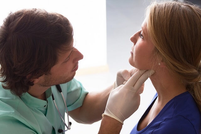 un medico examinando la garganta de una mujer