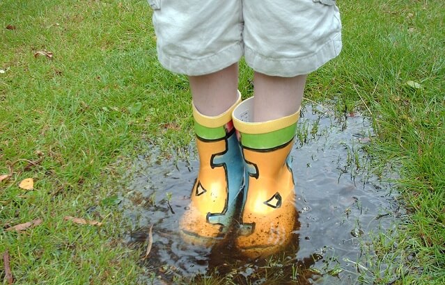 chico con botas de agua en un charco