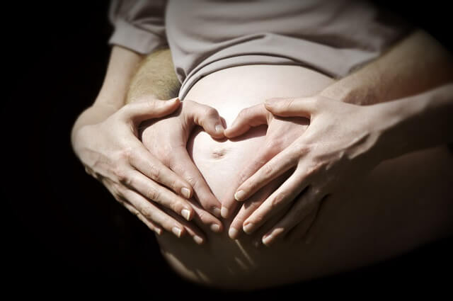tripa de embaraza con las manos en forma de corazon