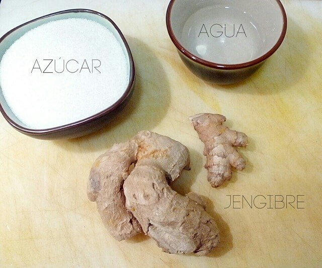 raiz de jengibre junto a un cuenco con azúcar y otro con agua