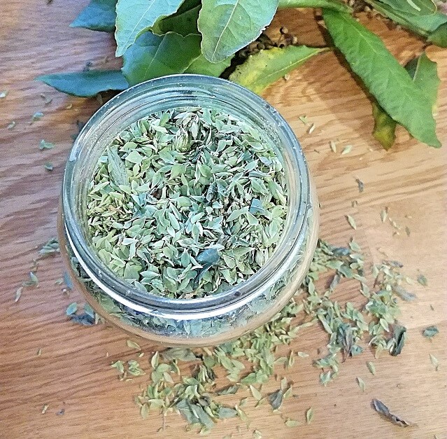 oregano seco en bote de cristal junto a unas hojas de laurel