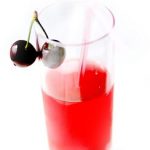 Vaso con zumo de cerezas decorado con unas cerezas