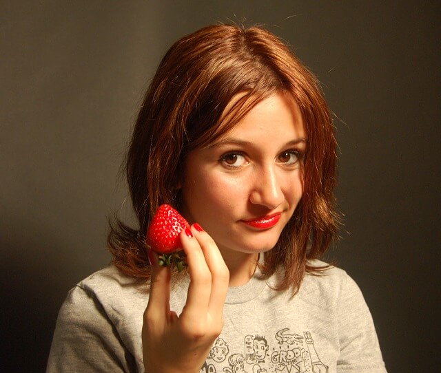 Chica joven con una fresa en la mano