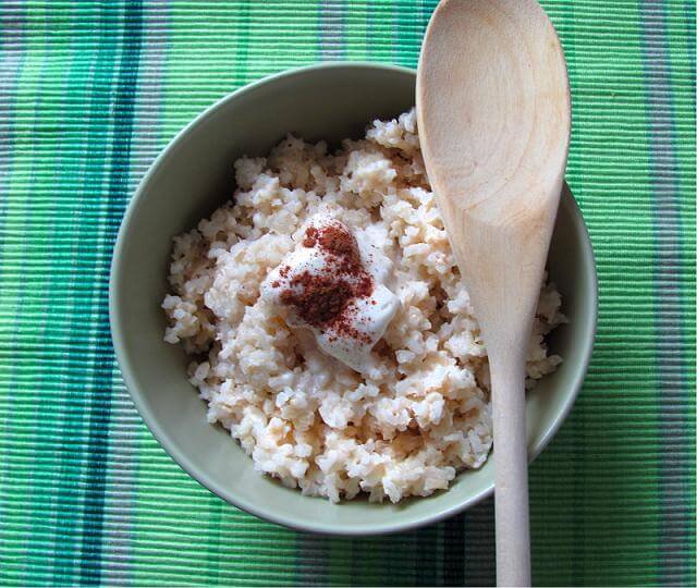 Cuenco con arroz con leche y una cuchara de madera