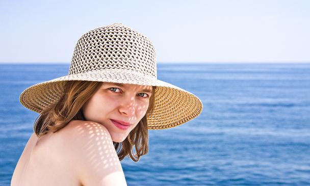 mujer bella con sombrero al lado del mar