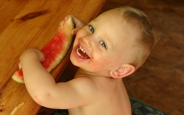 bebe sonriendo comiendo una sandia