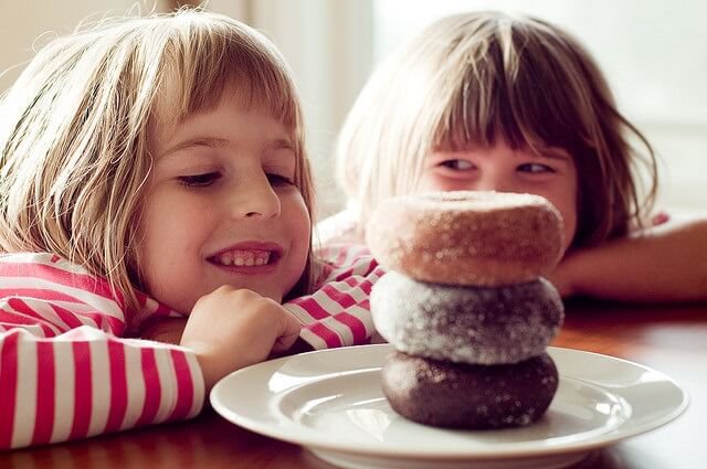 dos ninas mirando a los donuts con una sonrisa en la boca