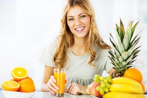 chica sonriente junto a frutas y zumos