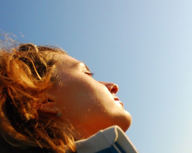 chica con los ojos cerrados mirando al sol