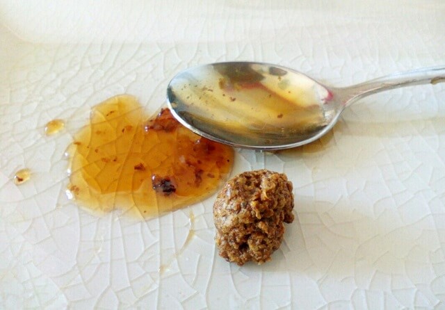 bolita de restos de panal de abejas en un plato junto a una cucharita