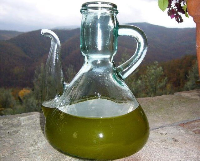 aceite de oliva recien extraido en envase de cristal junto a una bonita vista