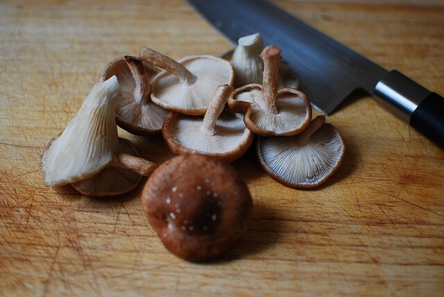 varios shiitakes en una tabla de cocina junto a un cuchillo