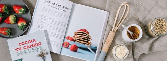 libro cocina tu cambio junto a unas fresas y utensilios de cocina